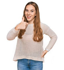 Young blonde woman wearing casual clothes doing happy thumbs up gesture with hand. approving...