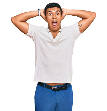 Young arab man wearing casual clothes crazy and scared with hands on head, afraid and surprised of shock with open mouth