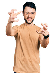 Fototapeta premium Hispanic man with beard wearing casual t shirt shouting frustrated with rage, hands trying to strangle, yelling mad