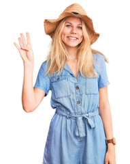 Young beautiful blonde woman wearing summer hat and dress showing and pointing up with fingers number four while smiling confident and happy.