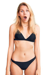 Obraz premium Young beautiful blonde woman wearing bikini afraid and shocked with surprise and amazed expression, fear and excited face.