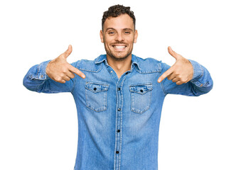 Young hispanic man wearing casual denim jacket looking confident with smile on face, pointing oneself with fingers proud and happy.