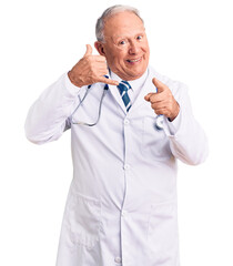 Senior handsome grey-haired man wearing doctor coat and stethoscope smiling doing talking on the telephone gesture and pointing to you. call me.