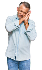 Middle age grey-haired man wearing casual clothes sleeping tired dreaming and posing with hands together while smiling with closed eyes.