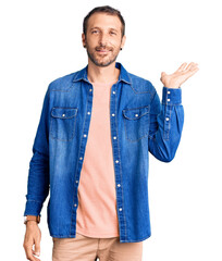 Young handsome man wearing casual clothes smiling cheerful presenting and pointing with palm of hand looking at the camera.