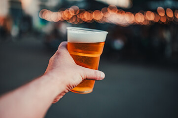 plastic cup glass with beer in hand. Outdoor summer festival