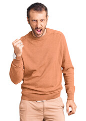 Young handsome man wearing casual clothes angry and mad raising fist frustrated and furious while shouting with anger. rage and aggressive concept.