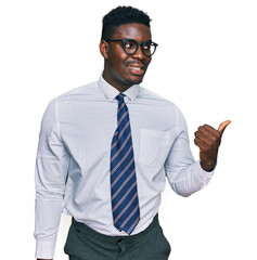 Handsome business black man wearing white shirt and tie smiling with happy face looking and pointing to the side with thumb up.