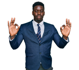 Handsome business black man wearing business suit and tie relax and smiling with eyes closed doing meditation gesture with fingers. yoga concept.