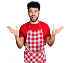 Young arab man with beard wearing cook apron celebrating crazy and amazed for success with arms raised and open eyes screaming excited. winner concept