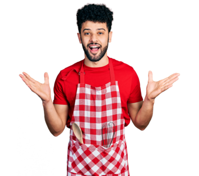 Young arab man with beard wearing cook apron celebrating crazy and amazed for success with arms raised and open eyes screaming excited. winner concept