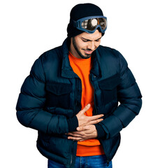 Young hispanic man with beard wearing snow wear and sky glasses with hand on stomach because indigestion, painful illness feeling unwell. ache concept.