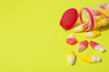 Jelly candies in jar on green background, space for text