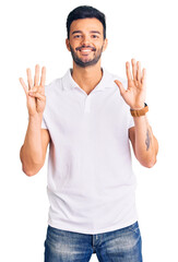 Fototapeta premium Young handsome hispanic man wearing casual clothes showing and pointing up with fingers number nine while smiling confident and happy.