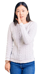 Young beautiful chinese woman wearing casual sweater hand on mouth telling secret rumor, whispering malicious talk conversation