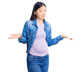 Young beautiful chinese woman pregnant expecting baby clueless and confused with open arms, no idea concept.