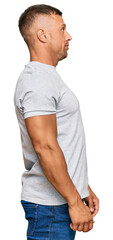 Handsome muscle man wearing casual grey tshirt looking to side, relax profile pose with natural face with confident smile.