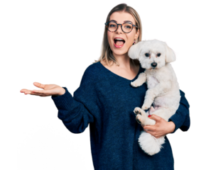 Young blonde woman hugging cute dog celebrating achievement with happy smile and winner expression with raised hand
