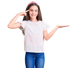 Fototapeta na wymiar Cute hispanic child girl wearing casual white tshirt confused and annoyed with open palm showing copy space and pointing finger to forehead. think about it.