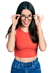 Obraz na płótnie Canvas Young hispanic woman wearing casual clothes and holding glasses smiling and laughing hard out loud because funny crazy joke.