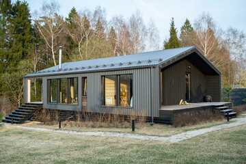 Beautiful appearance of a new house with an open veranda and green grass on a bright sunny day with a blue sky. 