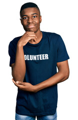 Young african american man wearing volunteer t shirt with hand on chin thinking about question, pensive expression. smiling and thoughtful face. doubt concept.