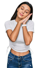 Young hispanic girl wearing casual white t shirt sleeping tired dreaming and posing with hands together while smiling with closed eyes.