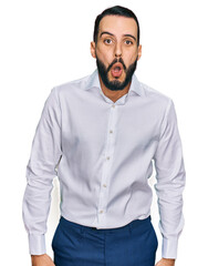 Young man with beard wearing business shirt afraid and shocked with surprise expression, fear and excited face.