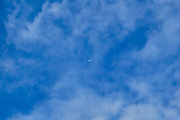 Blue sky with white clouds and moon in the day time. Natural background.