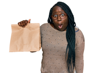 Young black woman with braids holding take away paper bag scared and amazed with open mouth for surprise, disbelief face