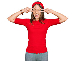 Young brunette woman wearing casual clothes doing peace symbol with fingers over face, smiling cheerful showing victory