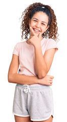 Beautiful kid girl with curly hair wearing casual clothes looking confident at the camera smiling with crossed arms and hand raised on chin. thinking positive.