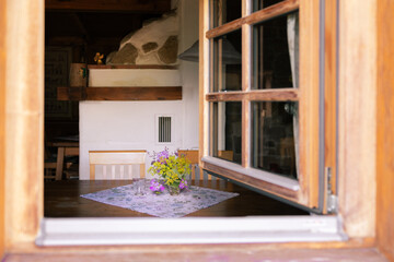 View through the window into a cozy peasant house with a table and a stove, Austria