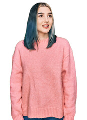 Young modern girl wearing pink wool winter sweater looking away to side with smile on face, natural expression. laughing confident.