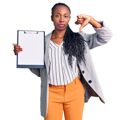 Young african american woman wearing business clothes holding clipboard with angry face, negative...