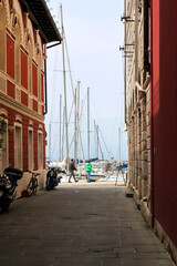 View from a narrow street of an old European city to boats and yachts in the port. Piran, Slovenia.