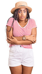 Young african american woman with braids wearing summer hat shaking and freezing for winter cold with sad and shock expression on face