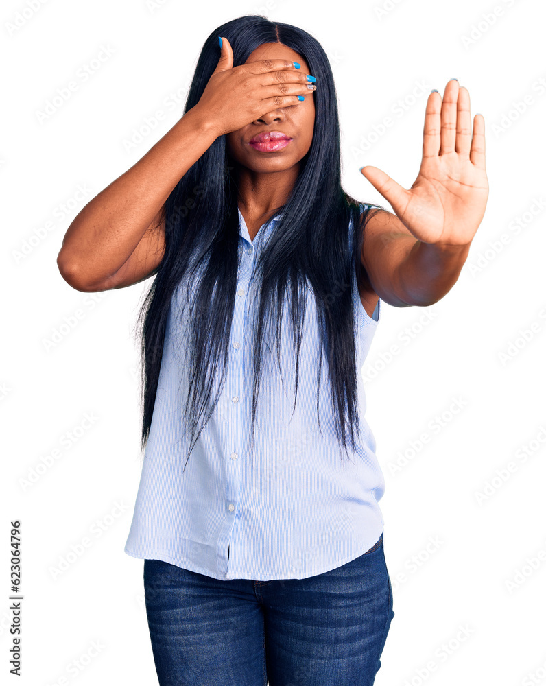 Sticker Young african american woman wearing casual clothes covering eyes with hands and doing stop gesture with sad and fear expression. embarrassed and negative concept.