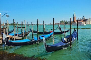 Fototapeta na wymiar View from Riva degli Schiavoni on gondolas moored with palines, gondolas riding the Giudecca Canal and San Giorgio Maggiore in Venice, Italy.
