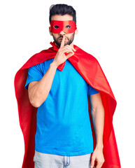 Young handsome man with beard wearing super hero costume asking to be quiet with finger on lips. silence and secret concept. © Krakenimages.com