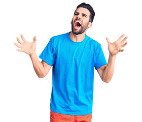 Naklejka premium Young handsome man with beard wearing casual t-shirt crazy and mad shouting and yelling with aggressive expression and arms raised. frustration concept.