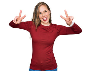 Young blonde woman wearing casual clothes smiling with tongue out showing fingers of both hands doing victory sign. number two.