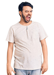 Young hispanic man wearing casual clothes winking looking at the camera with sexy expression, cheerful and happy face.