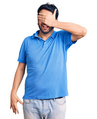 Young hispanic man wearing casual clothes smiling and laughing with hand on face covering eyes for surprise. blind concept.