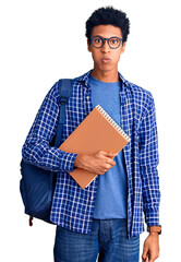 Young african american man wearing student backpack holding book puffing cheeks with funny face. mouth inflated with air, crazy expression.