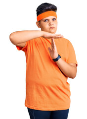 Little boy kid wearing sportswear doing time out gesture with hands, frustrated and serious face
