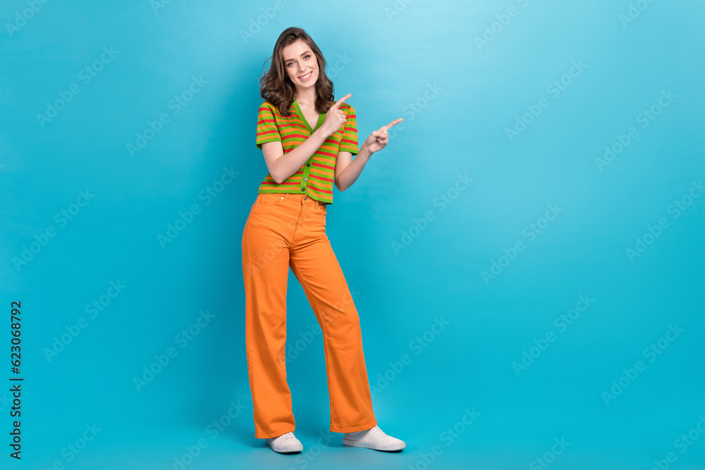 Poster full length photo of cheerful cute girl wear striped shirt trousers indicating at offer empty space 