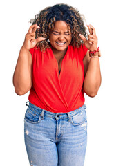 Young african american plus size woman wearing casual style with sleeveless shirt gesturing finger crossed smiling with hope and eyes closed. luck and superstitious concept.
