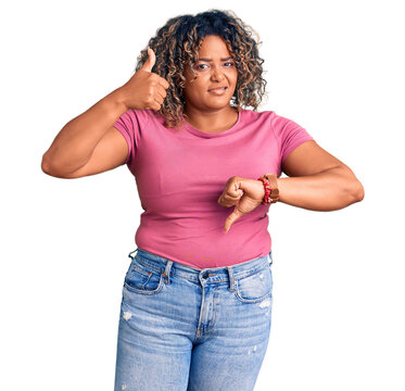 Young african american plus size woman wearing casual clothes doing thumbs up and down, disagreement and agreement expression. crazy conflict