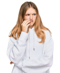 Beautiful young caucasian girl wearing casual sweatshirt looking stressed and nervous with hands on mouth biting nails. anxiety problem.